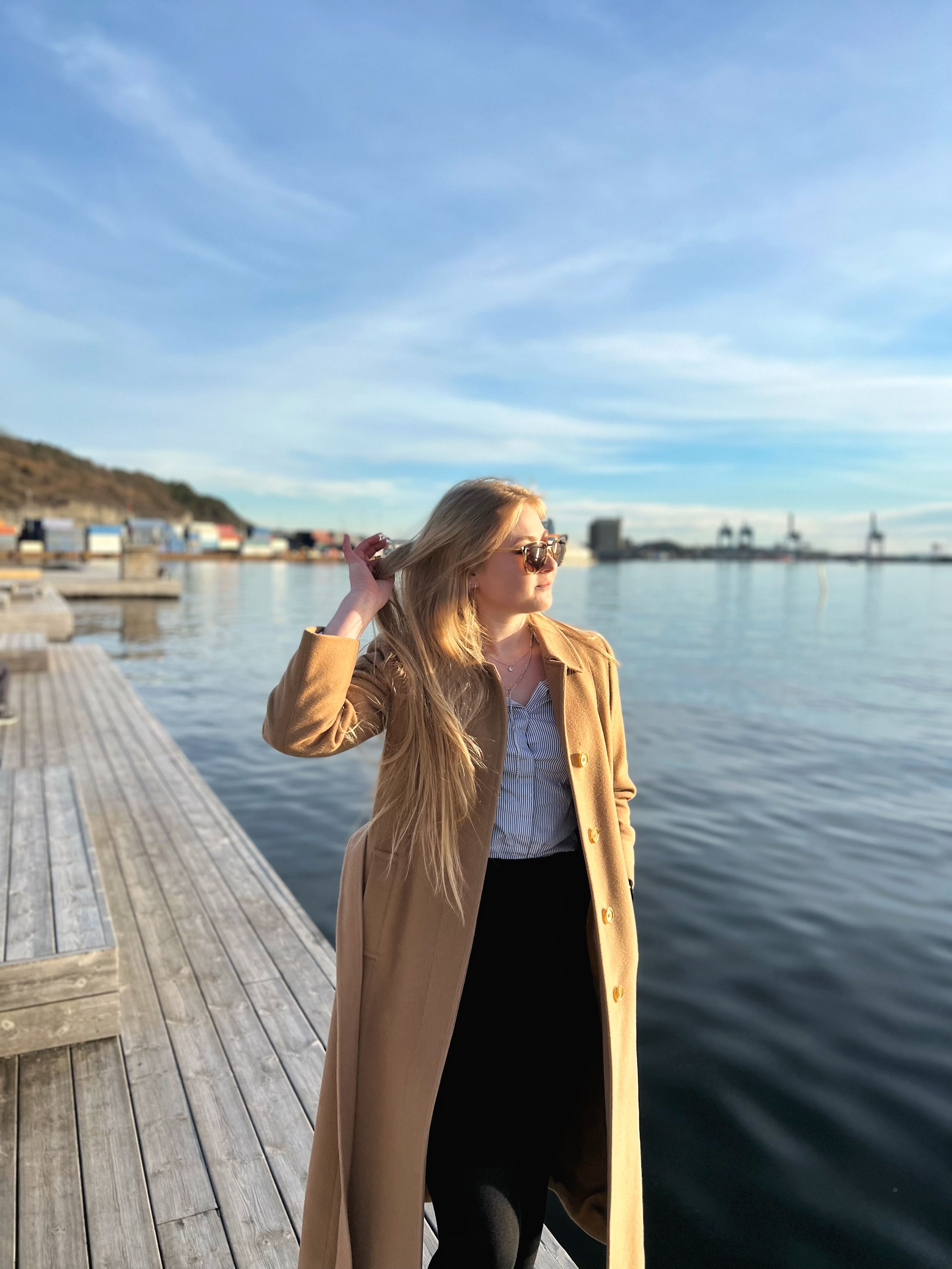 Woman wearing a business outfit and trench coat by the sea