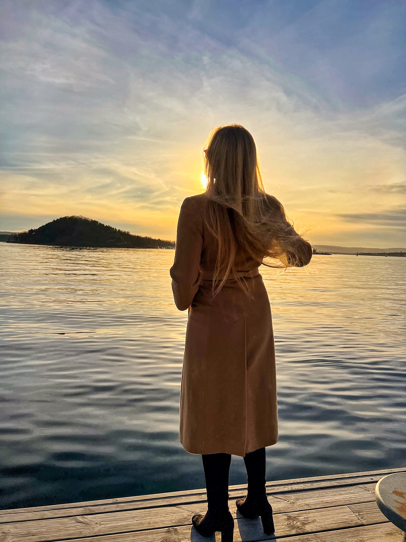 Woman wearing a business outfit and trench coat by the sea