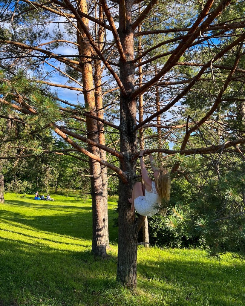 Woman climbing a tree in a white dress