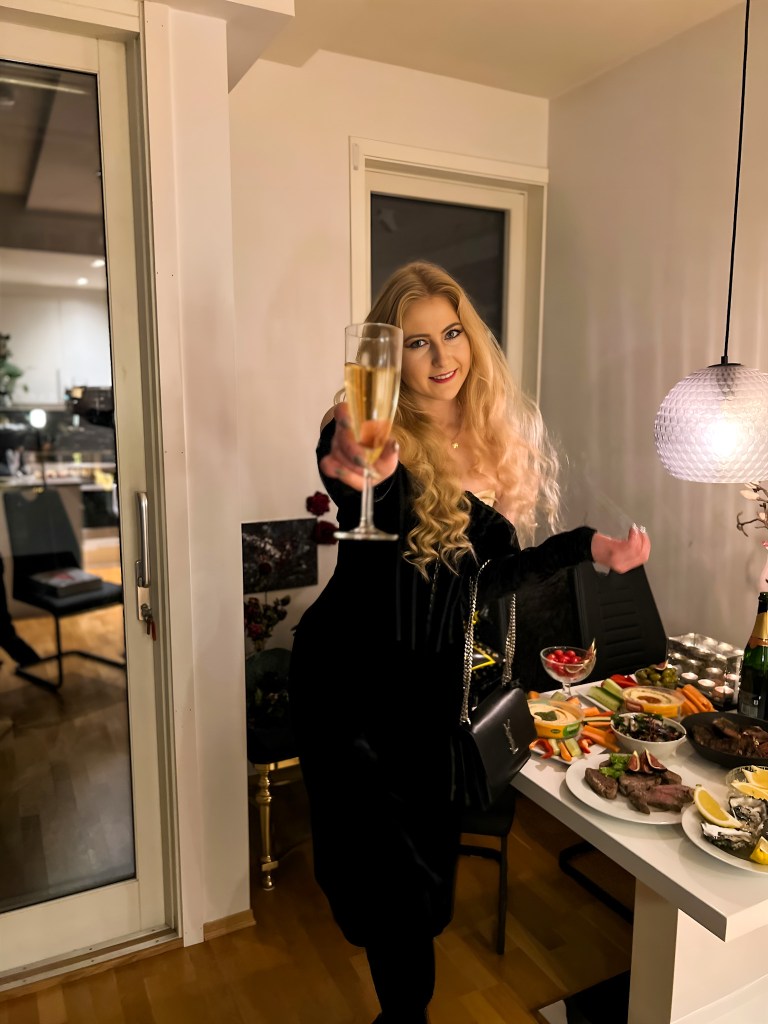Woman in a black dress at New Years holding a champagn glass
