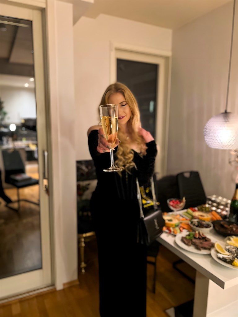 Woman in a black dress at New Years holding a champagn glass