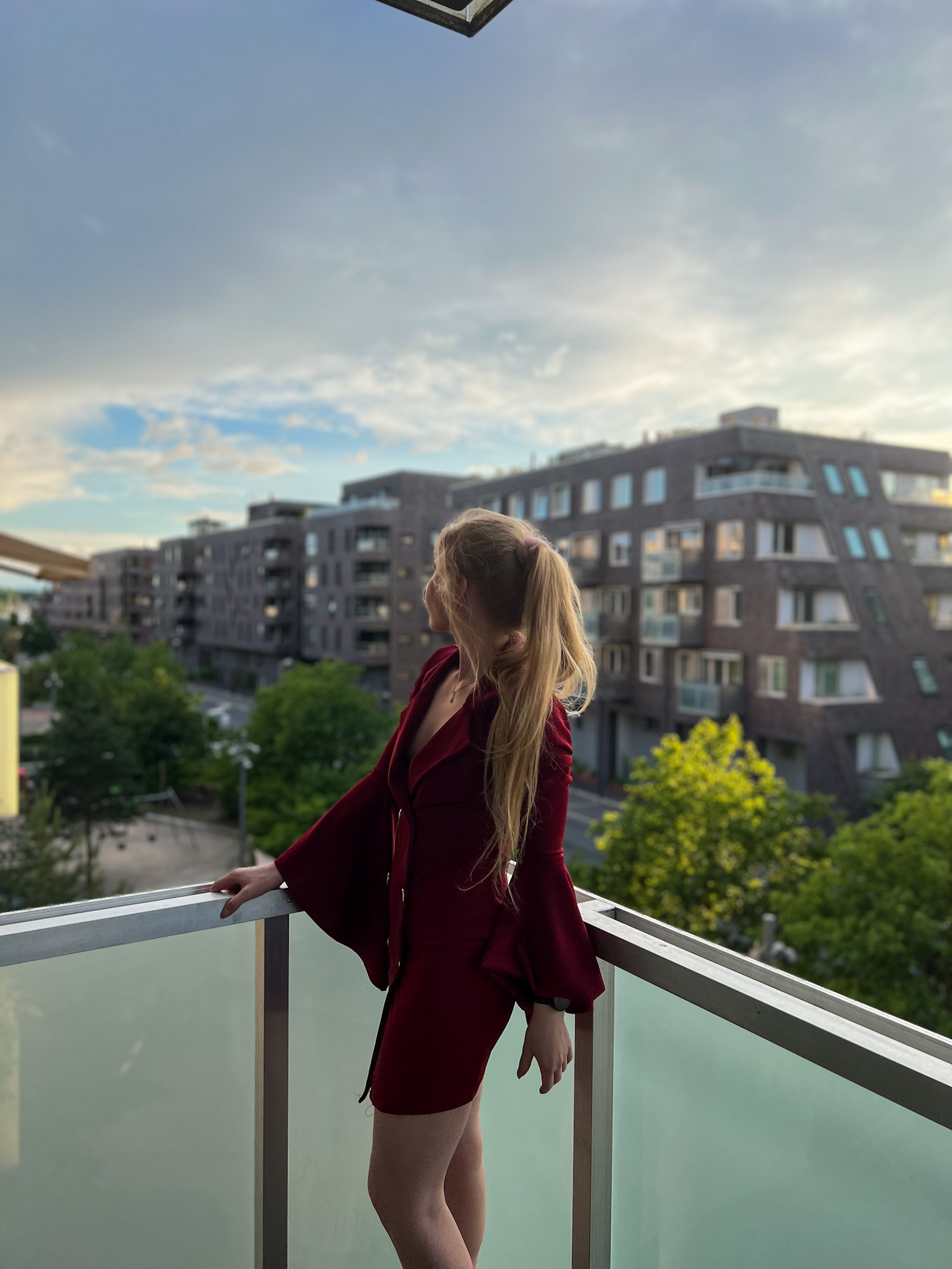 Wearing a red dress and looking out from the balcony view