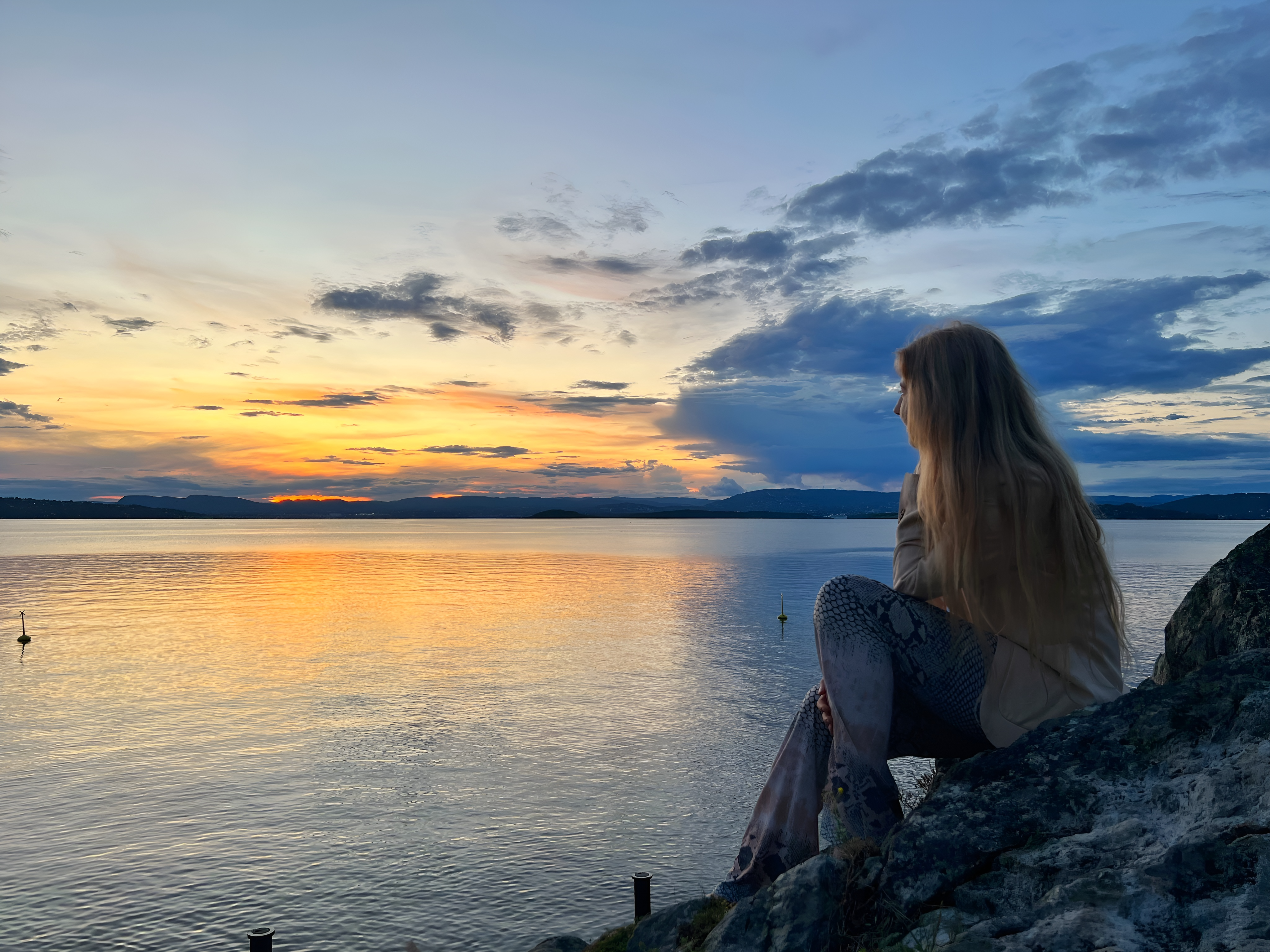 Sunsethour where a woman looks into the horizon by the sea.