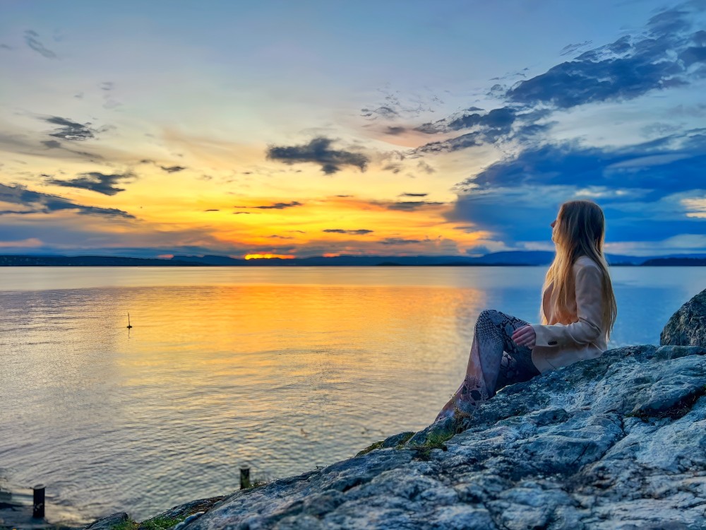 Sunset by the sea with a lady watching over the horizon