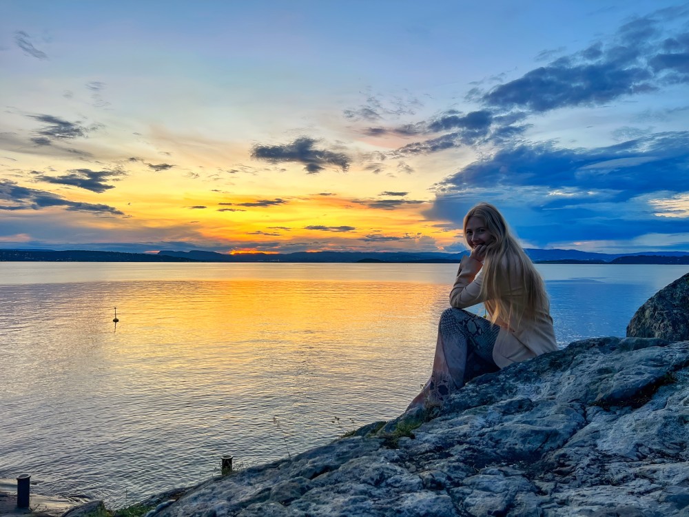Sunset by the sea with a lady watching over the horizon