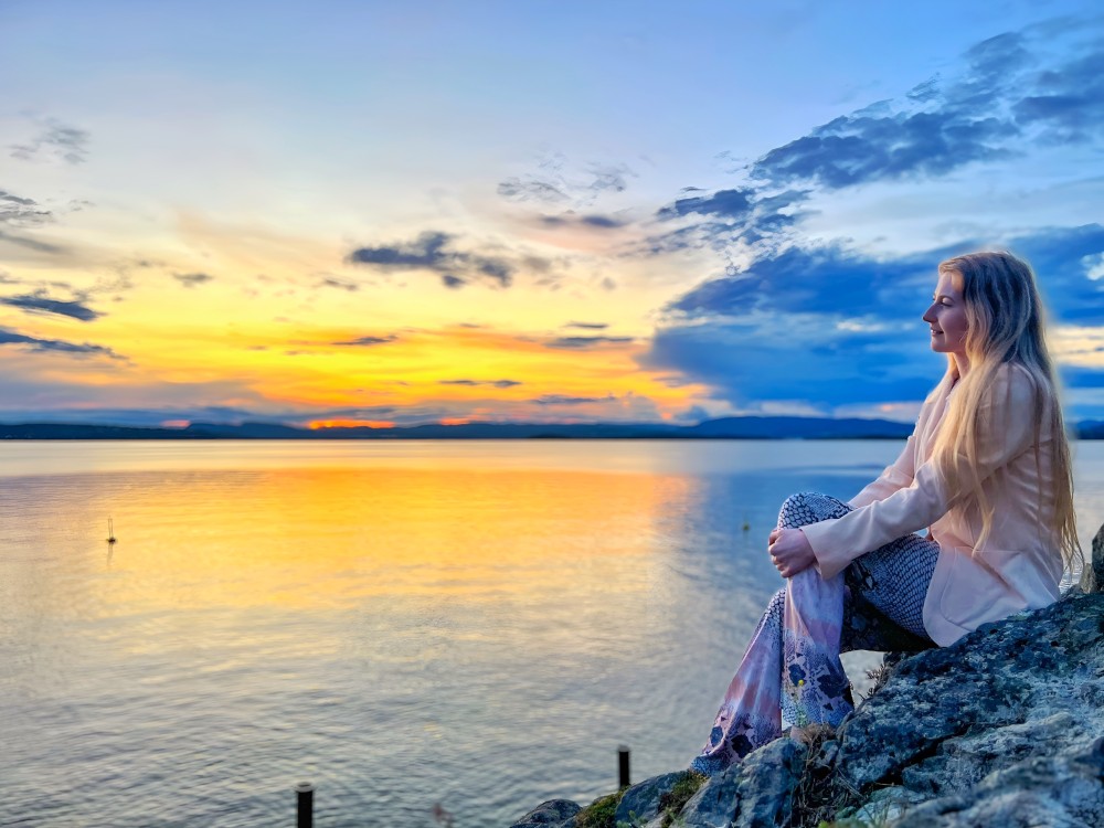 Sunset by the sea with a lady watching over the horizon